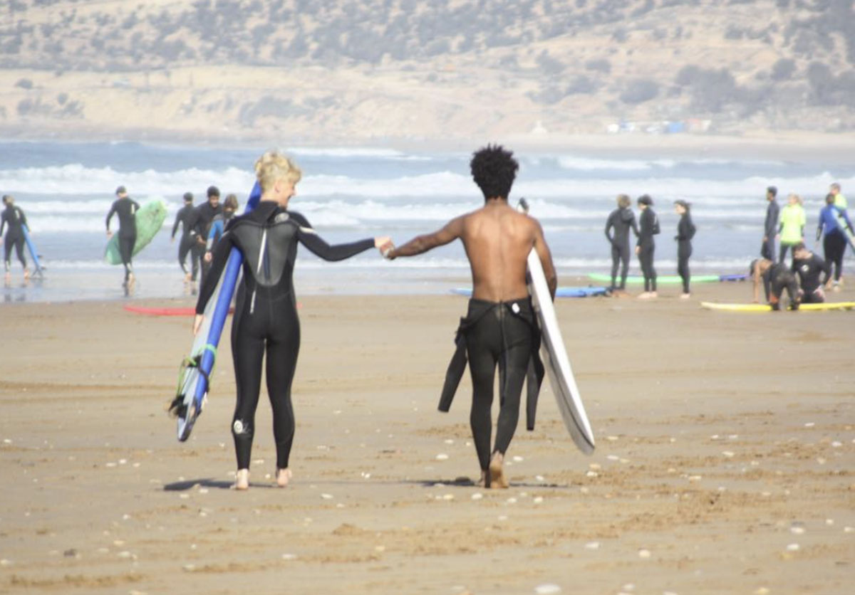 Two guests fist bumping on the beach, ready to catch waves in Taghazout, Morocco. Surf adventure and excitement