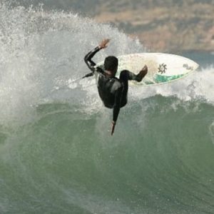 Surfer performing a stylish flip on a big wave at Taghazout, Morocco. Action-packed surfing at Nomad Surf Camp