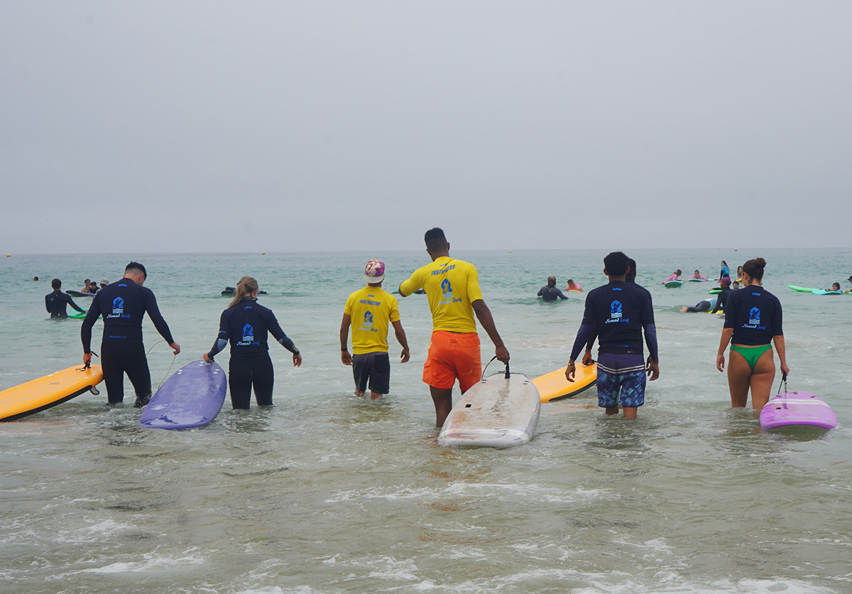 Guests at Nomad Surf Camp Morocco ready to catch their first wave in Tamraght. Surf lesson adventure on the beach