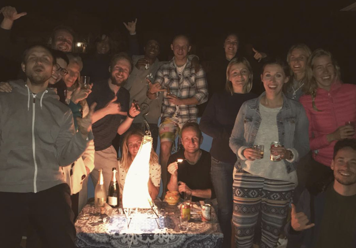 Group of guests celebrating at a rooftop party at night in Taghazout, Morocco. Fun and social evening