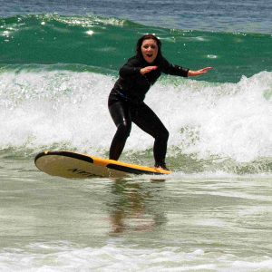 Young girl catching her first wave at Devil’s Rock surf spot in Tamraght with Nomad Surf Camp