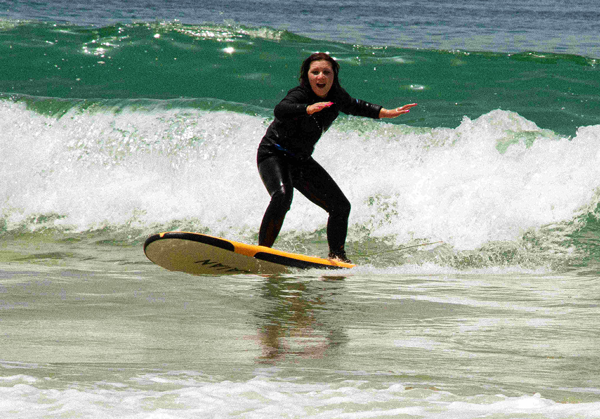 Young girl catching her first wave at Devil’s Rock surf spot in Tamraght with Nomad Surf Camp