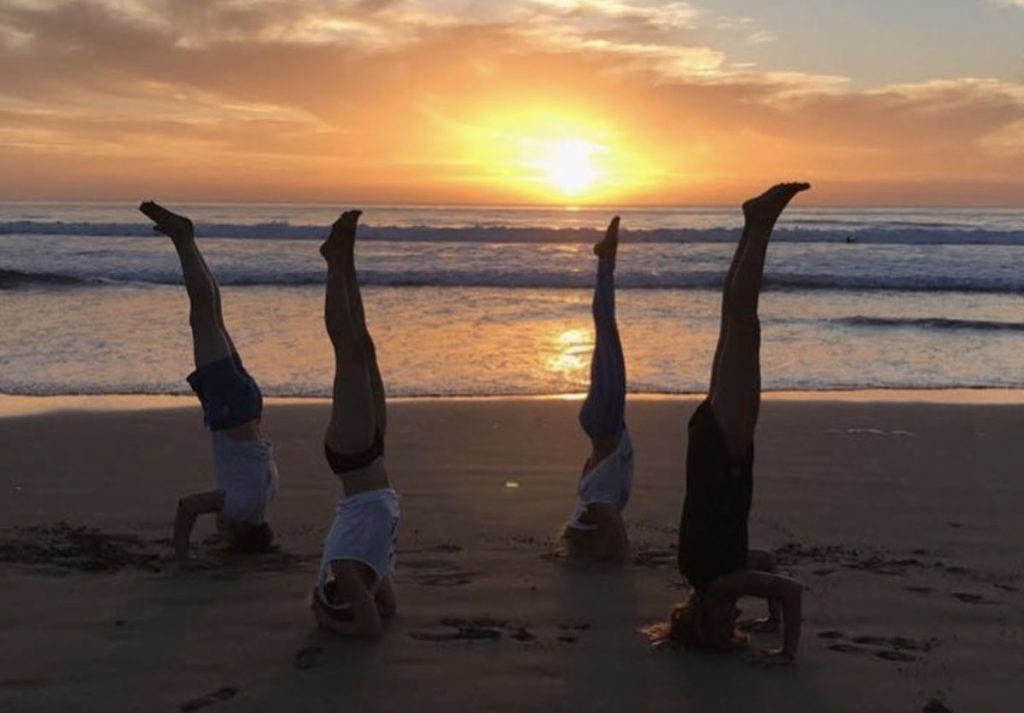 Group of guests practicing yoga on the beach at sunset in Taghazout, Morocco. Relaxation and wellness by the ocean