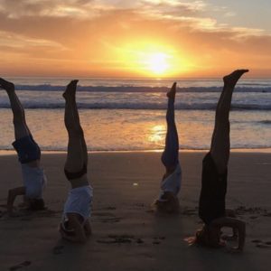 Group of guests practicing yoga on the beach at sunset in Taghazout, Morocco. Relaxation and wellness by the ocean