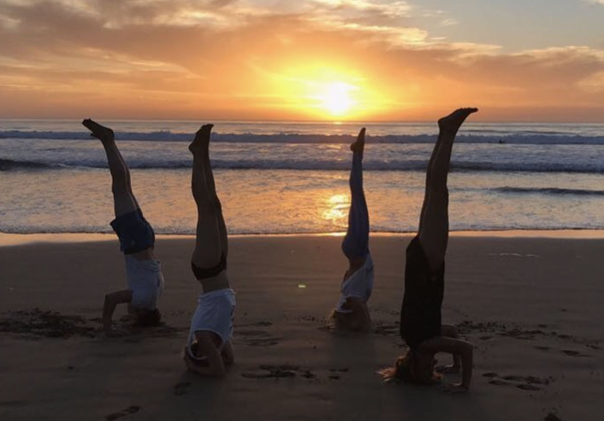 Group of guests practicing yoga on the beach at sunset in Taghazout, Morocco. Relaxation and wellness by the ocean